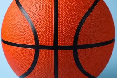Photo of One orange basketball ball on light blue background, closeup