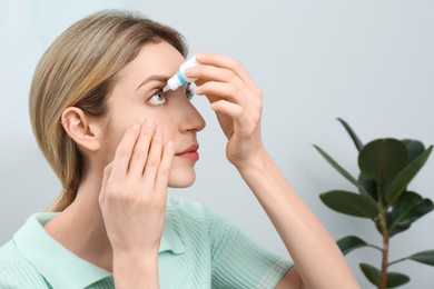 Photo of Young woman using eye drops at home