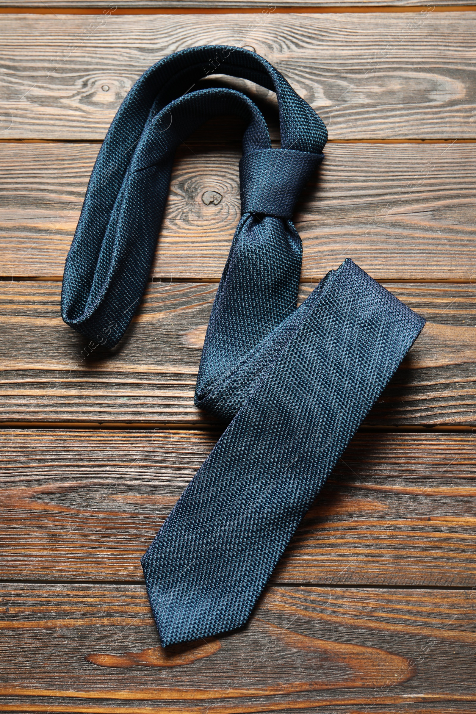 Photo of One blue necktie on wooden table, top view