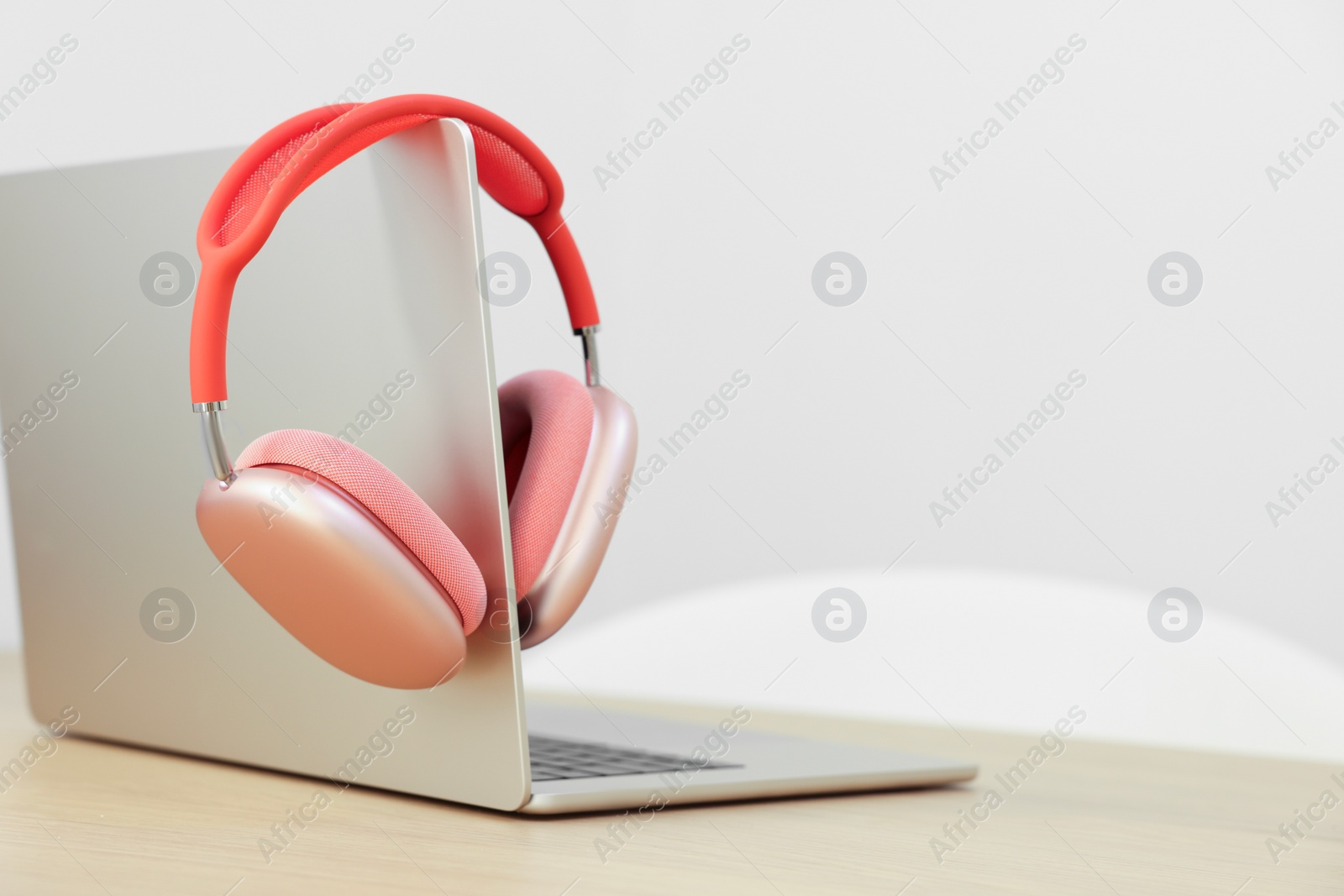 Photo of Modern laptop and headphones on wooden table. Space for text