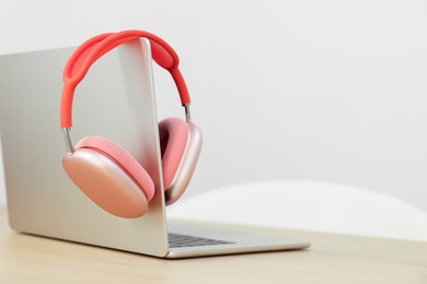 Photo of Modern laptop and headphones on wooden table. Space for text