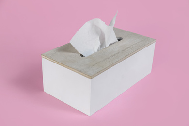 Photo of Holder with paper tissues on pink background