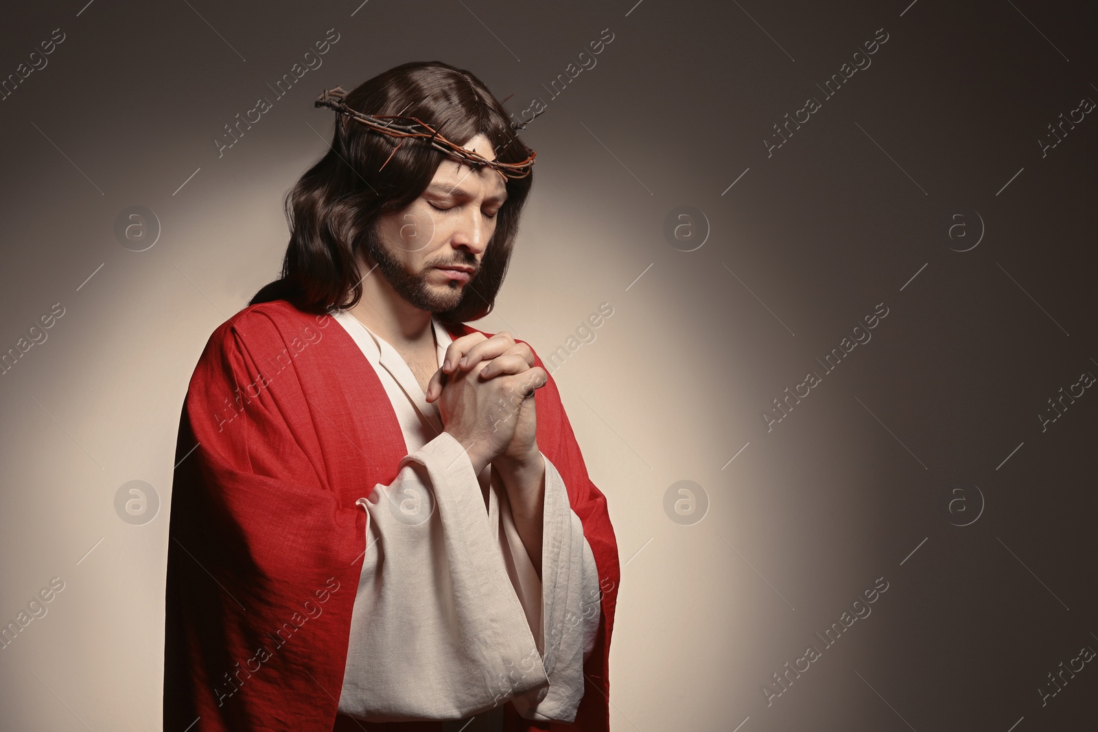 Photo of Jesus Christ with crown of thorns praying on beige background, space for text