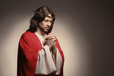 Photo of Jesus Christ with crown of thorns praying on beige background, space for text