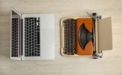 Old typewriter and laptop on wooden table, flat lay. Concept of technology progress