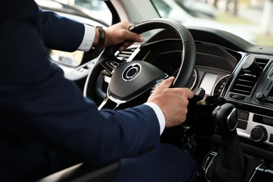Photo of Man driving his car, closeup view of hands on steering wheel