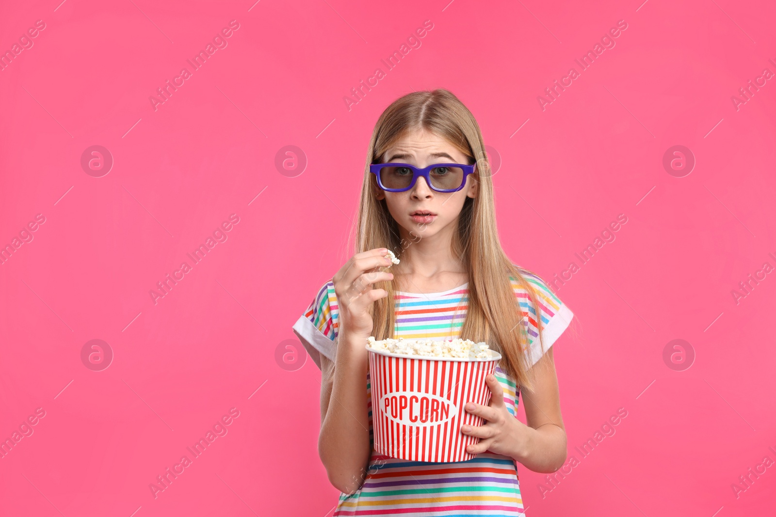 Photo of Emotional teenage girl with 3D glasses and popcorn during cinema show on color background