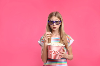 Photo of Emotional teenage girl with 3D glasses and popcorn during cinema show on color background