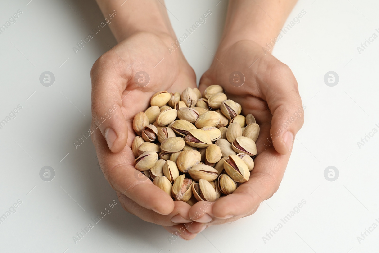 Photo of Woman holding tasty roasted pistachio nuts on white background, closeup