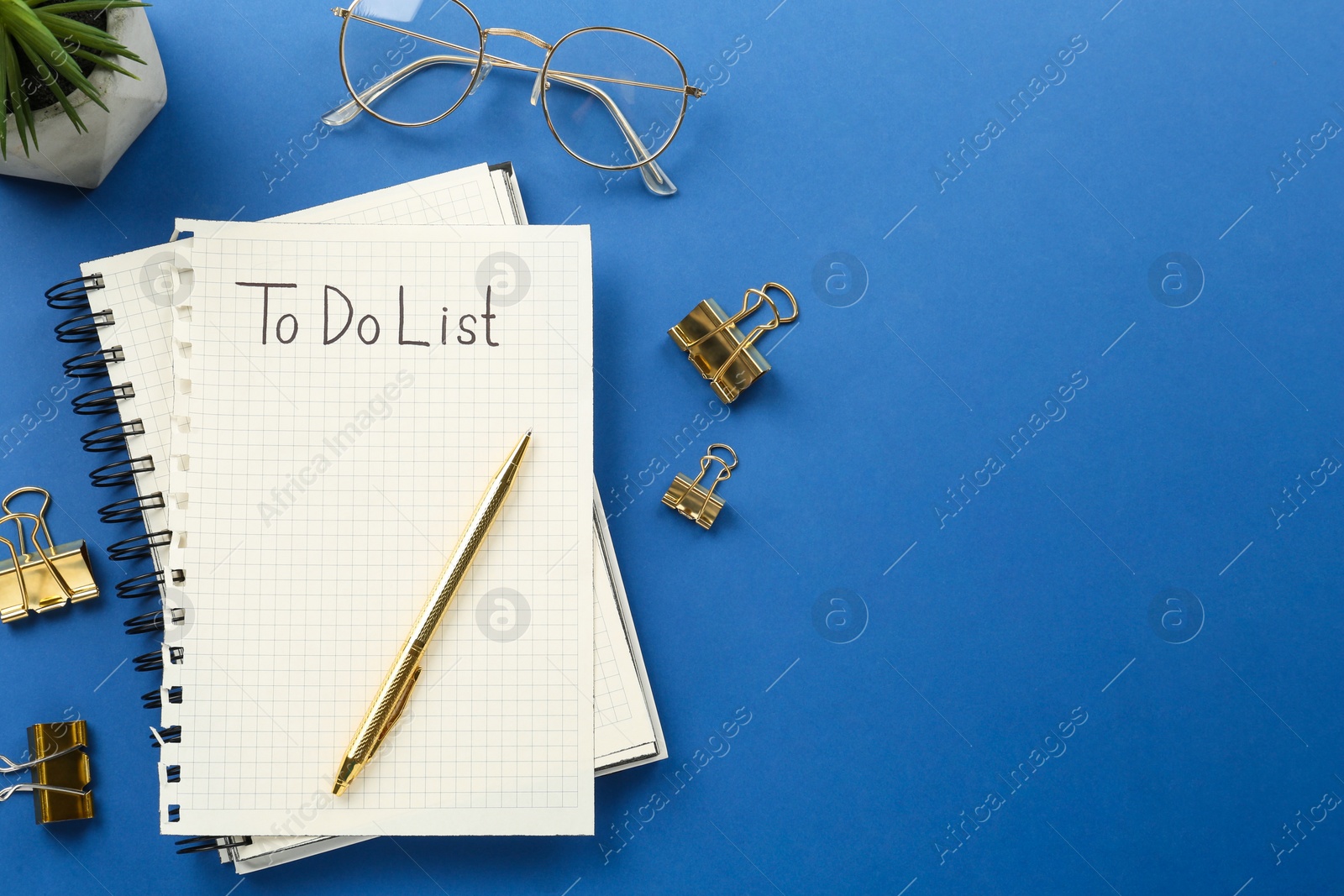 Photo of Flat lay composition with unfilled To Do list and glasses on blue background, space for text