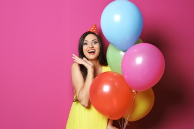 Photo of Young woman with bright balloons on color background. Birthday celebration