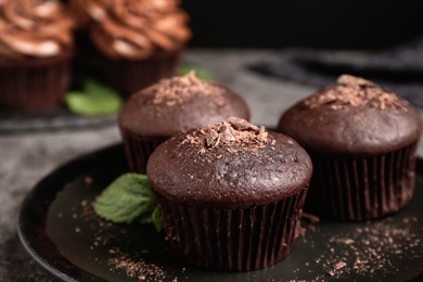 Delicious chocolate muffins on black plate, closeup