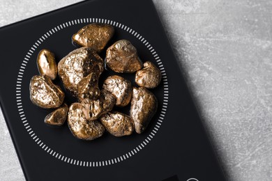 Photo of Digital scales with gold nuggets on light grey table, top view