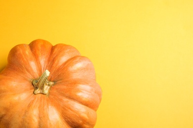 Photo of Fresh ripe pumpkin on yellow background, top view with space for text. Holiday decoration