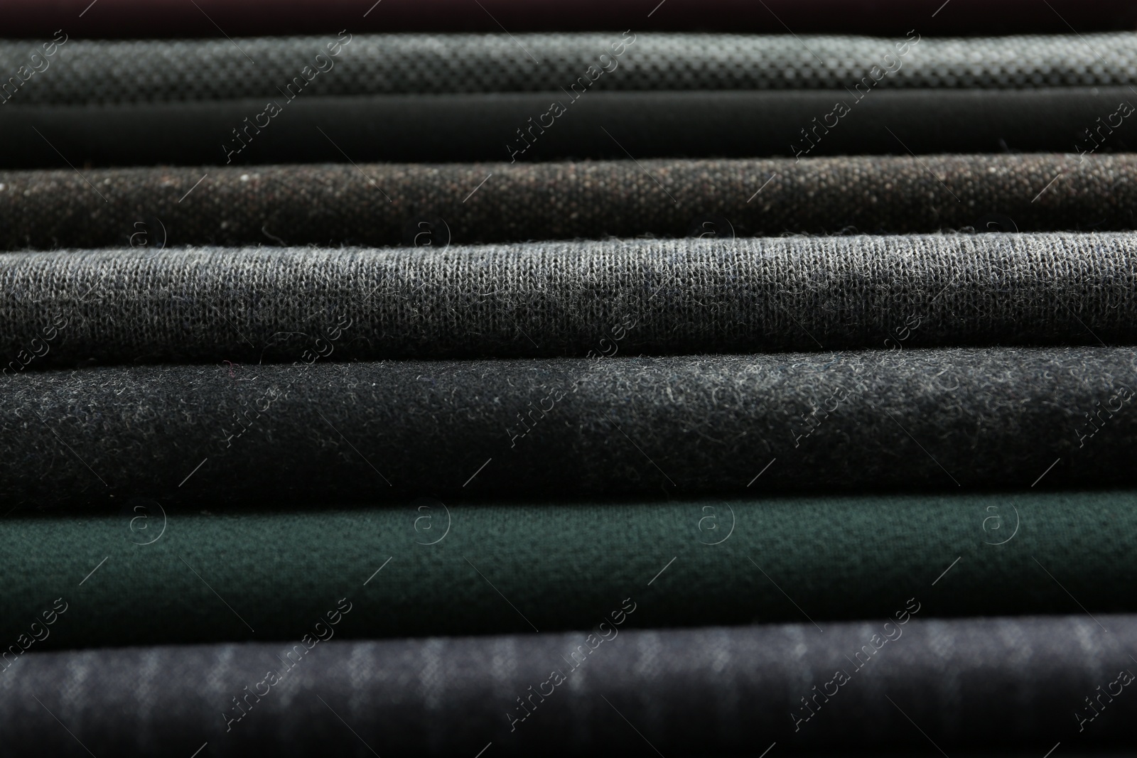 Photo of Stack of different fabric samples as background, closeup. Textile texture