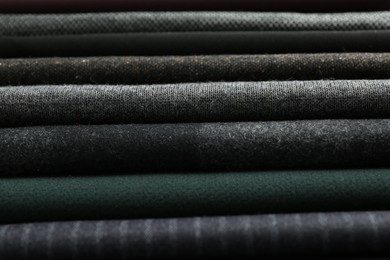 Stack of different fabric samples as background, closeup. Textile texture