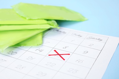 Calendar and menstrual pads on color background, closeup with space for text. Gynecological care