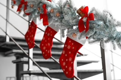 Photo of Santa stockings and garland on railing indoors. Christmas decor idea