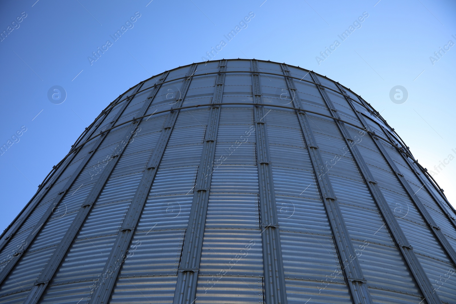 Photo of Modern granary for storing cereal grains against blue sky, low angle view