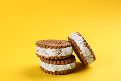 Photo of Sweet delicious ice cream cookie sandwiches on yellow background