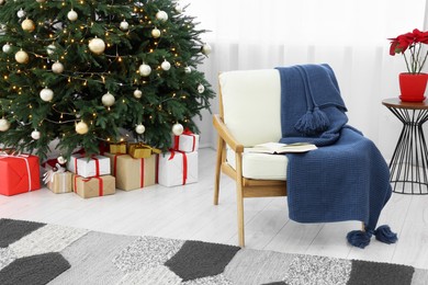Photo of Beautiful Christmas tree with festive lights, gifts and armchair in living room. Interior design