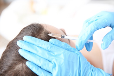 Photo of Young woman with hair loss problem receiving injection in clinic