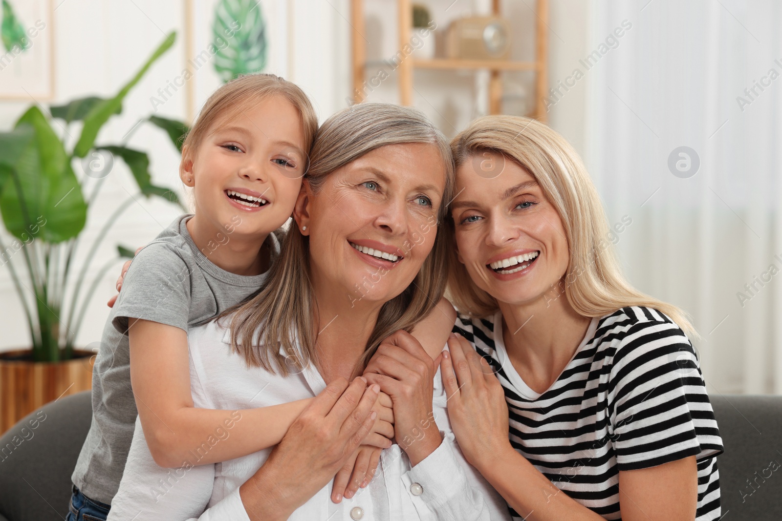 Photo of Three generations. Happy grandmother, her daughter and granddaughter at home