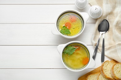 Photo of Delicious bouillon served on white wooden table, flat lay. Space for text