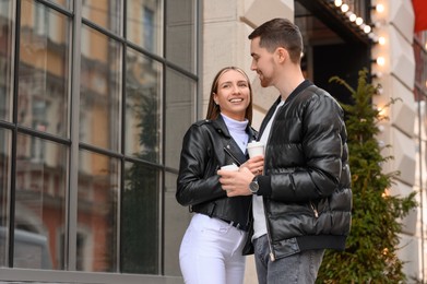 Photo of Lovely young couple with cups of coffee enjoying time together outdoors. Romantic date