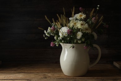 Photo of Bouquet of beautiful wild flowers and spikelets on wooden table against black background. Space for text