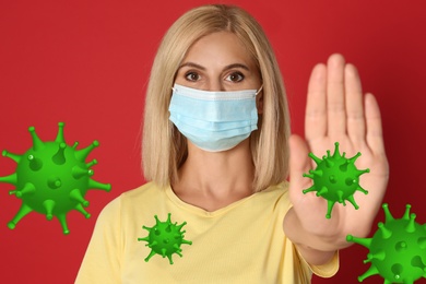 Image of Stop Covid-19 outbreak. Woman wearing medical mask surrounded by virus on red background