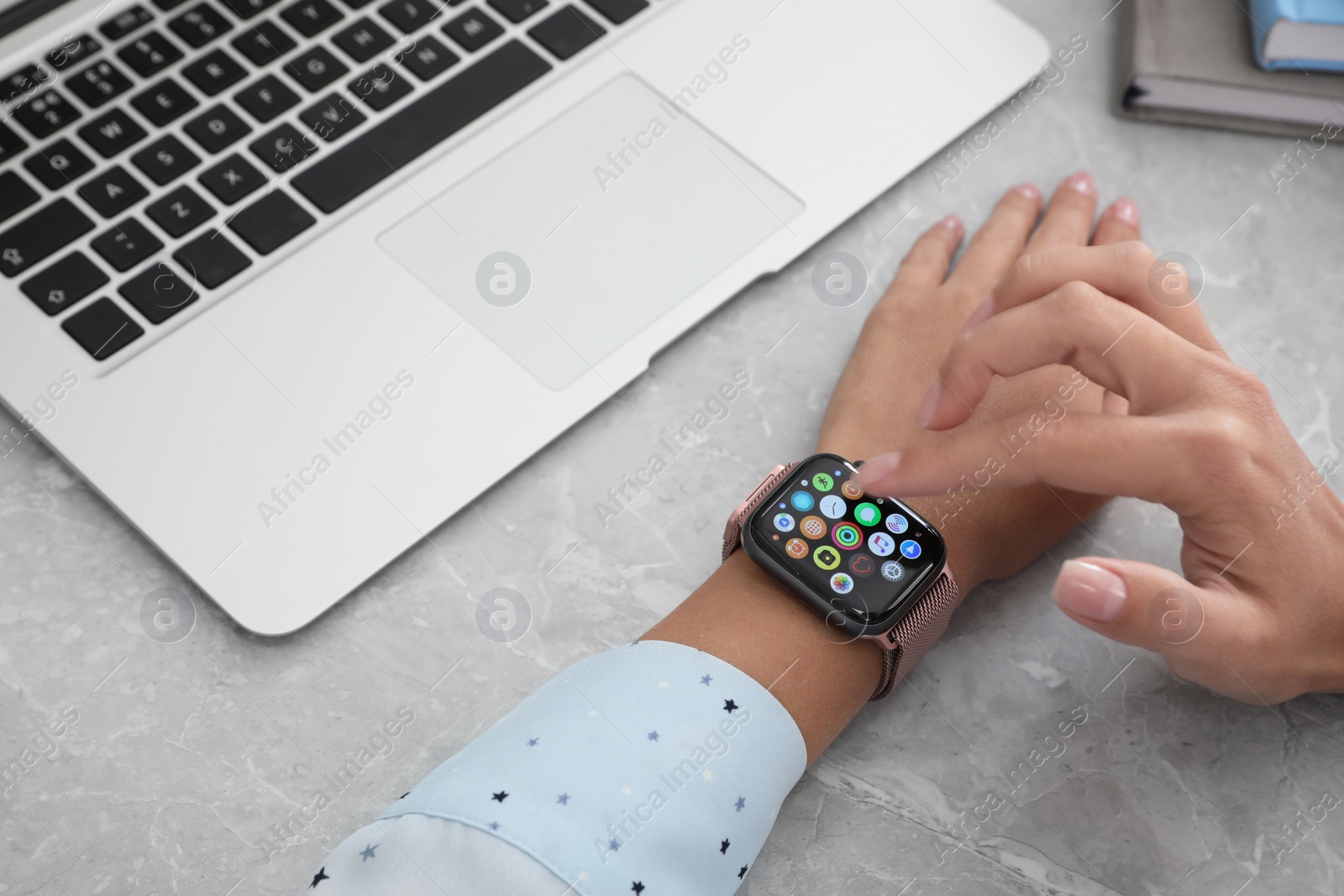 Image of MYKOLAIV, UKRAINE - SEPTEMBER 19, 2019: Woman using Apple Watch at grey table, closeup