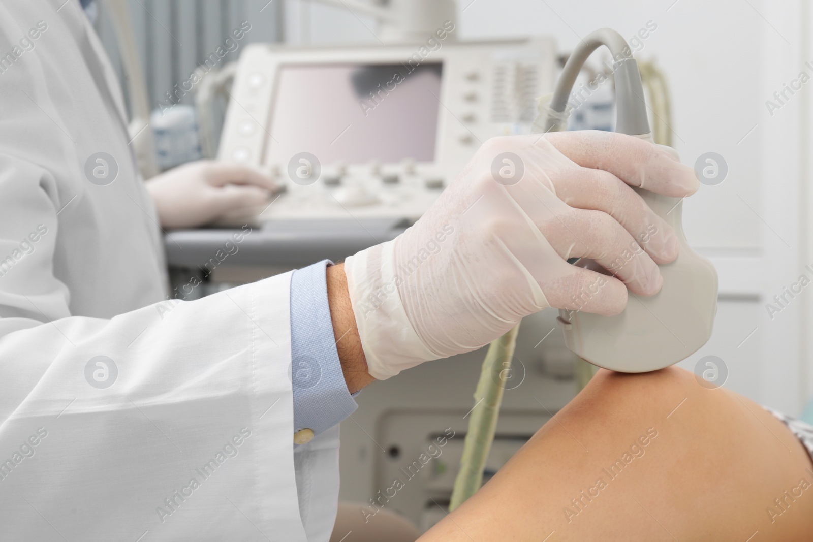 Photo of Doctor conducting ultrasound examination of patient's knee in clinic, closeup