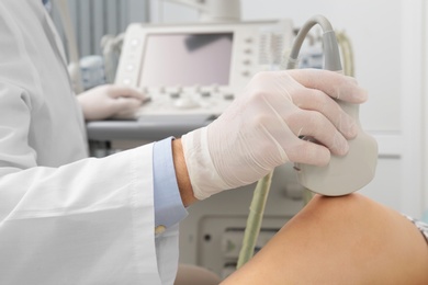 Photo of Doctor conducting ultrasound examination of patient's knee in clinic, closeup