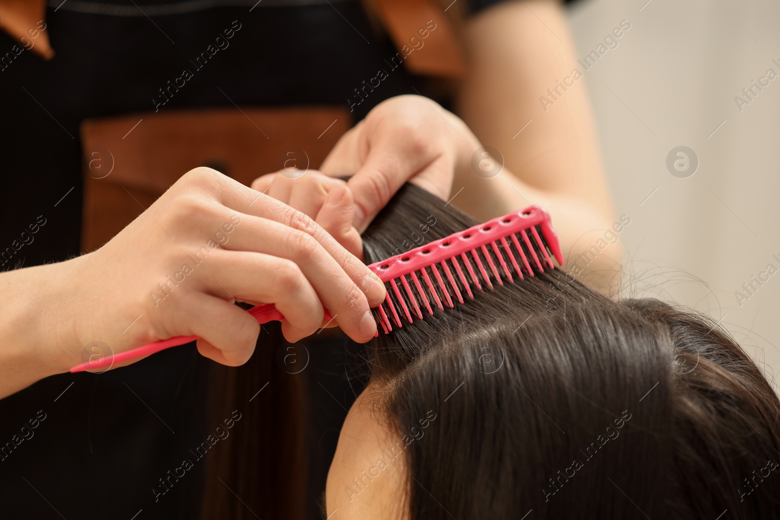 Photo of Hair styling. Professional hairdresser combing woman's hair indoors, closeup