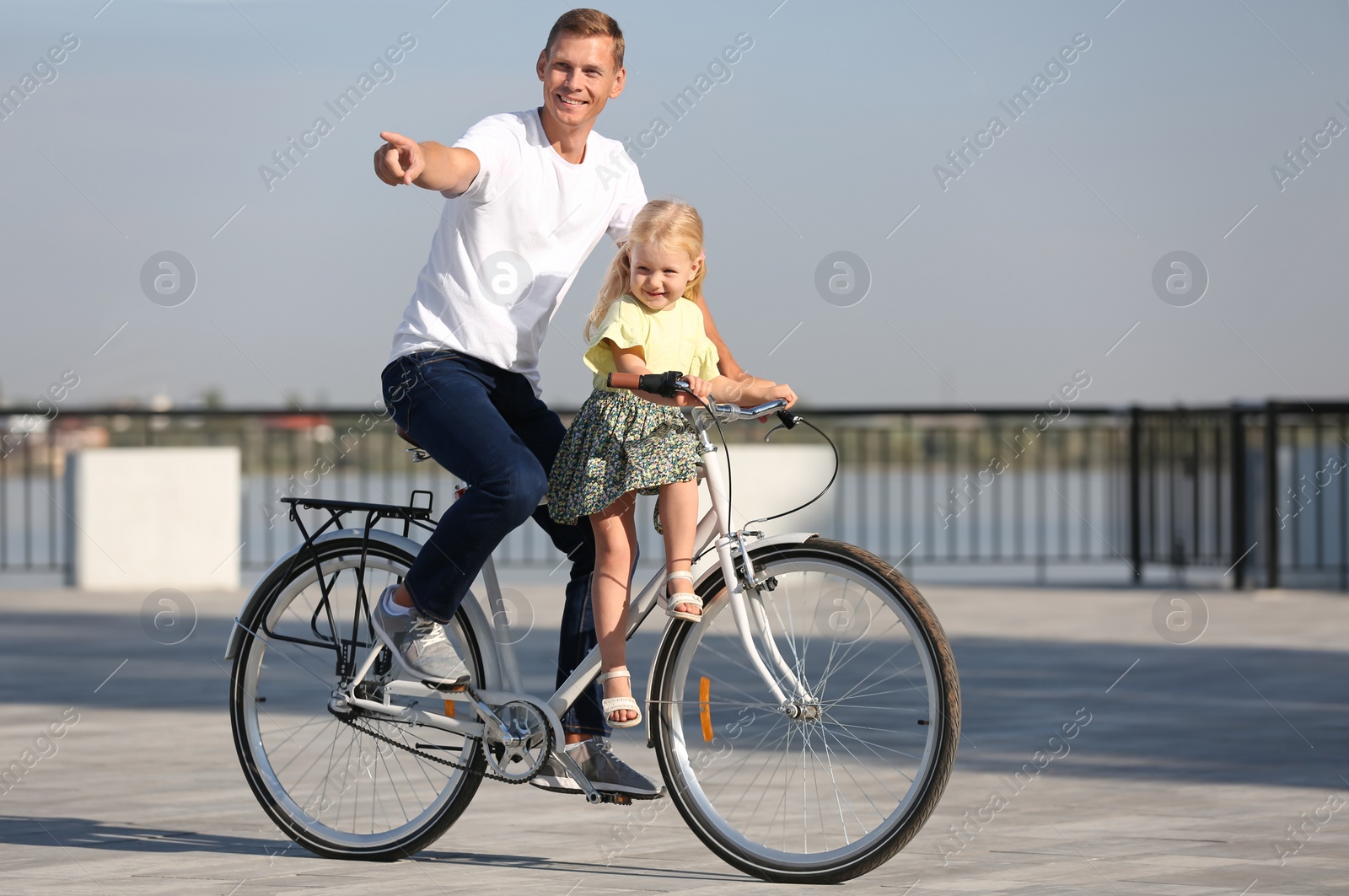 Photo of Father and daughter riding bicycle outdoors on sunny day