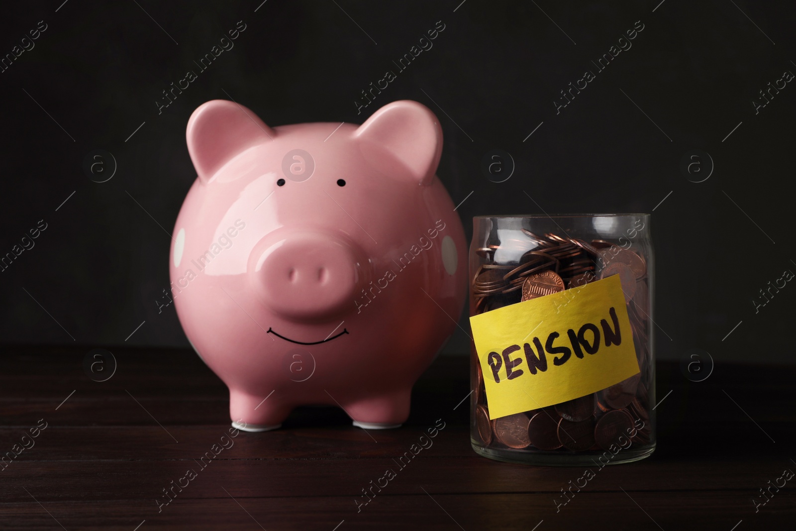 Photo of Piggy bank and jar of coins with word PENSION on table