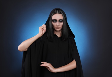 Photo of Mysterious witch with spooky eyes on color background
