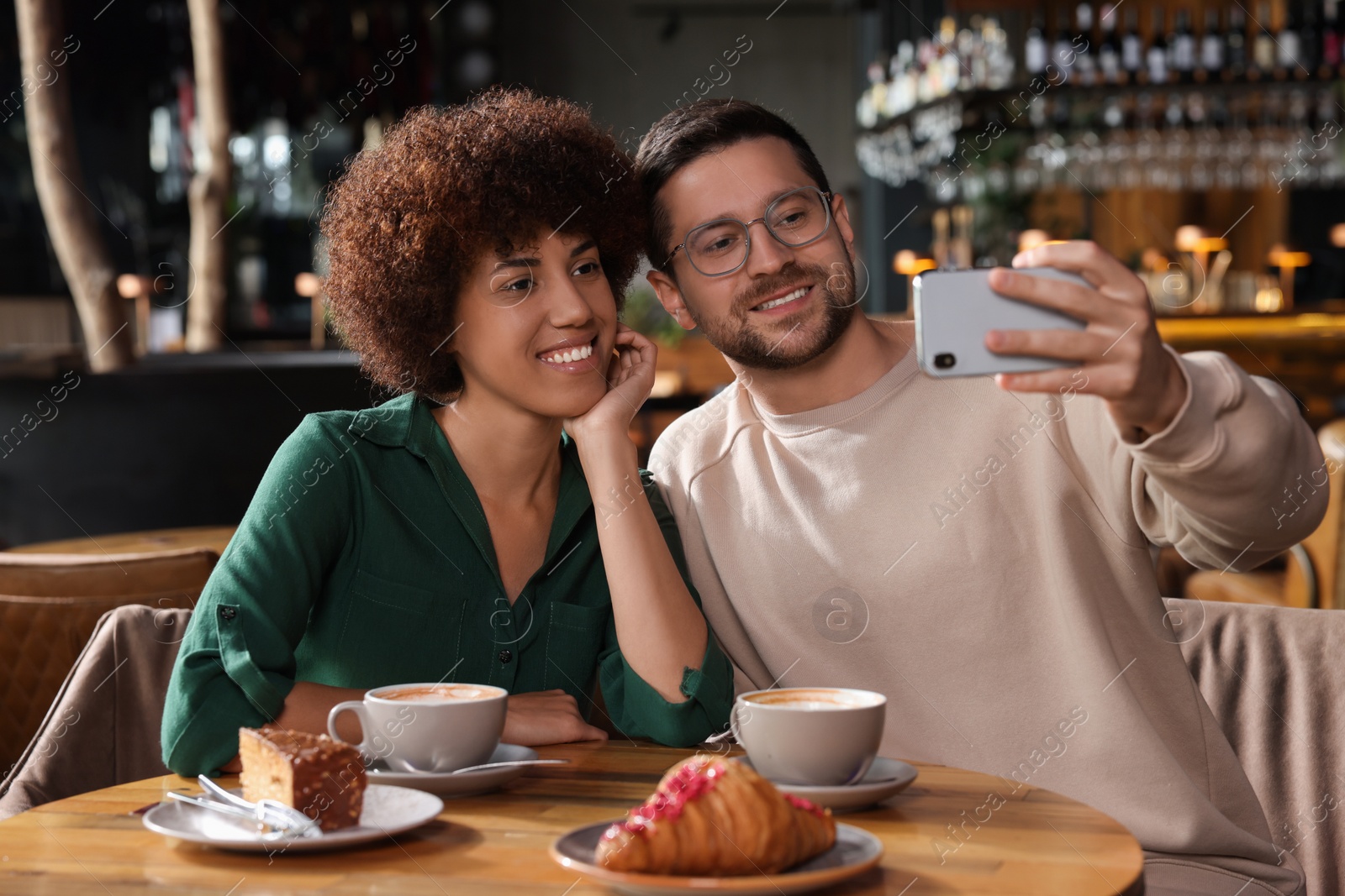 Photo of International dating. Happy couple taking selfie in cafe