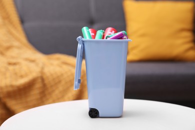 Mini recycling bin with different types of batteries on white table indoors