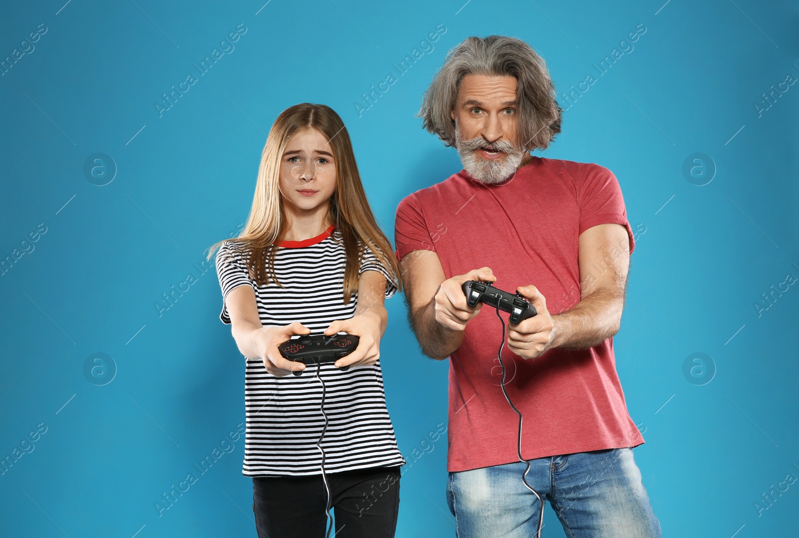 Photo of Mature man and teenage girl playing video games with controllers on color background