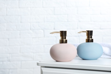 Photo of Stylish soap dispensers on table against blurred background. Space for text