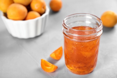 Photo of Jar with tasty apricot jam on table