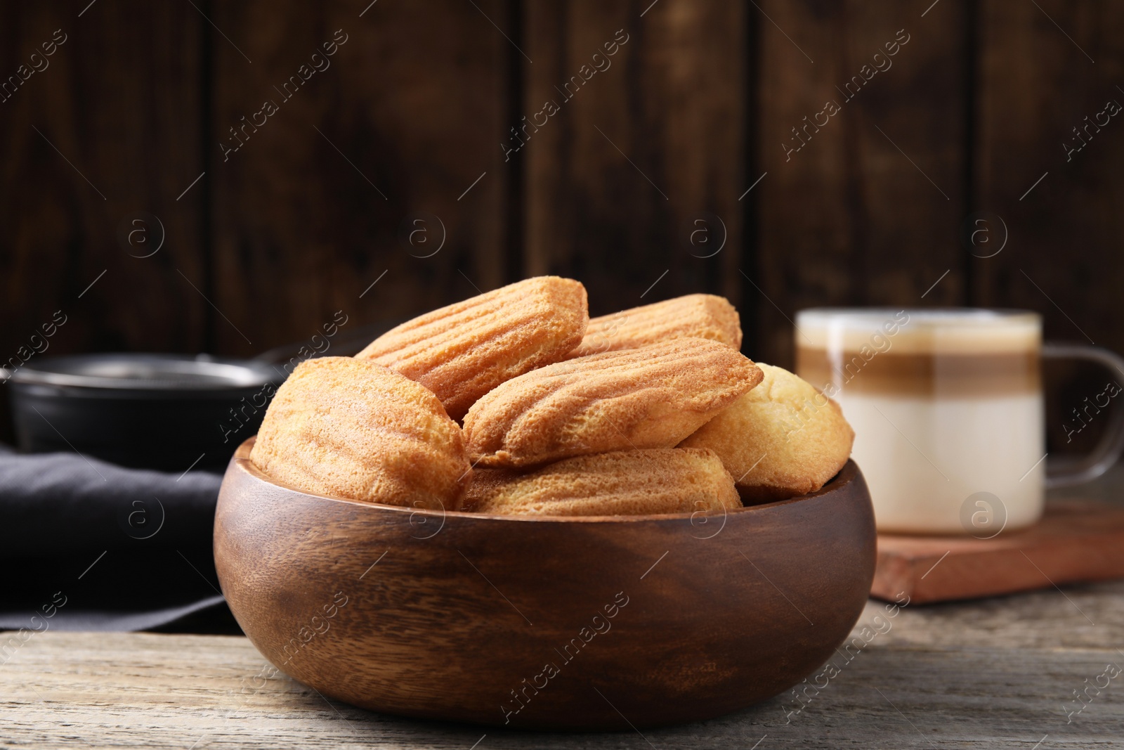 Photo of Tasty madeleine cookies in bowl on wooden table