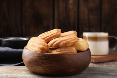 Photo of Tasty madeleine cookies in bowl on wooden table