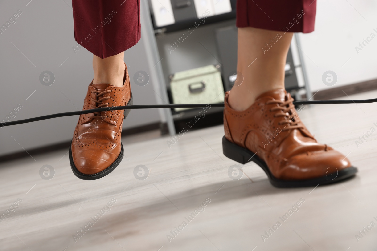 Photo of Woman tripping over cable in office, closeup