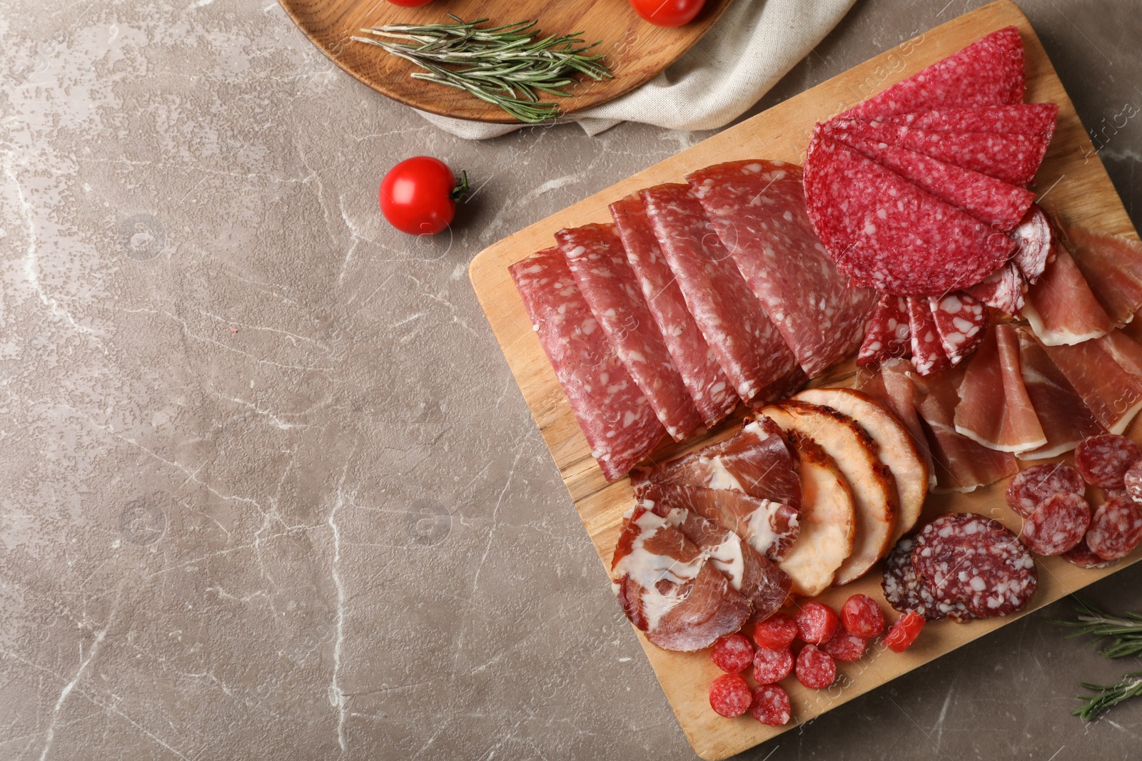 Photo of Cutting board with different sliced meat products on table, flat lay. Space for text