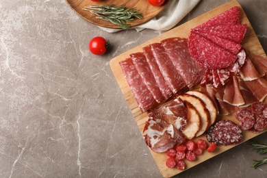 Cutting board with different sliced meat products on table, flat lay. Space for text