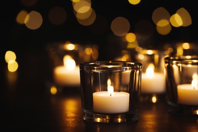 Photo of Burning candle on table against blurred background. Funeral symbol