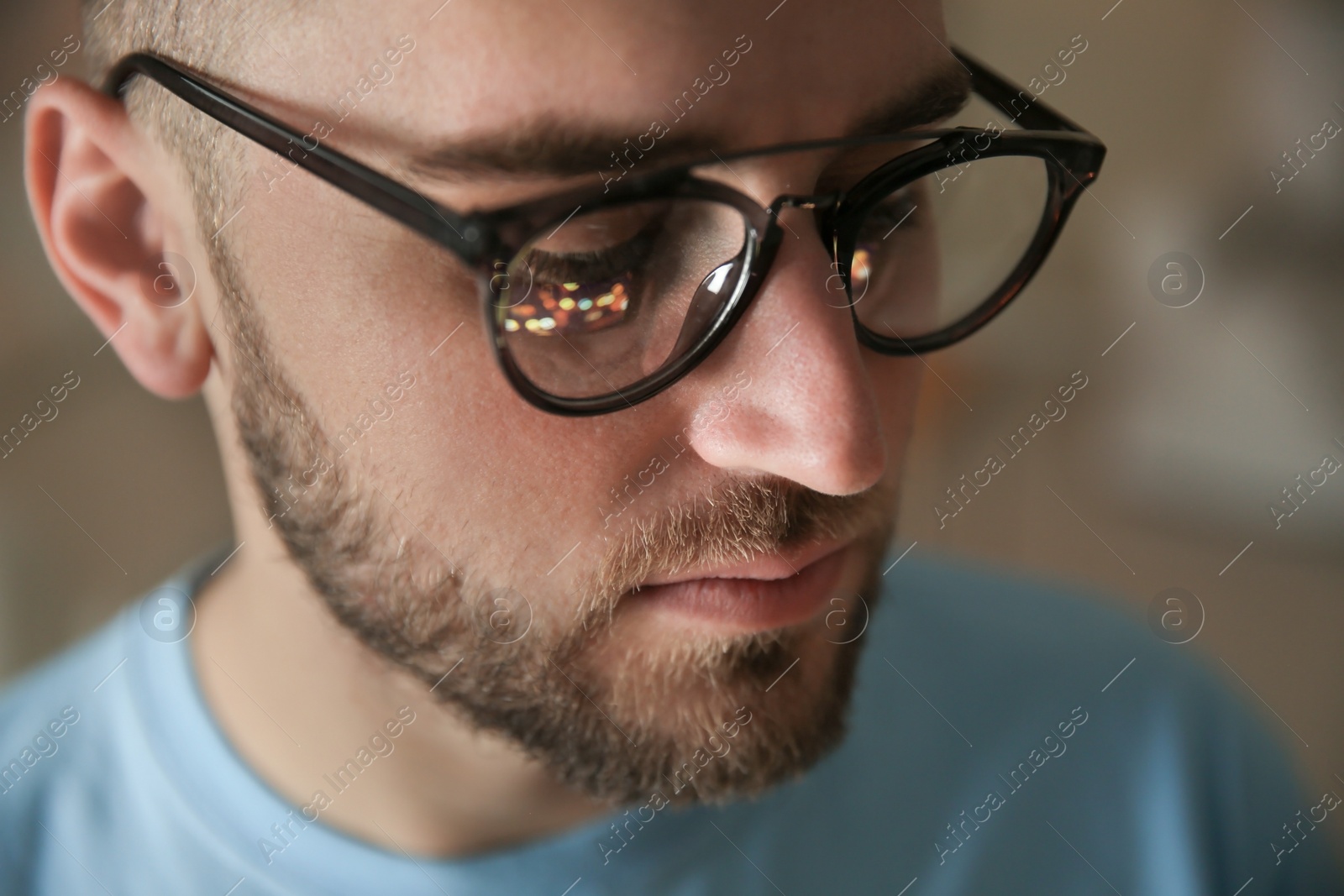 Photo of Young man wearing glasses on blurred background, closeup. Ophthalmology service